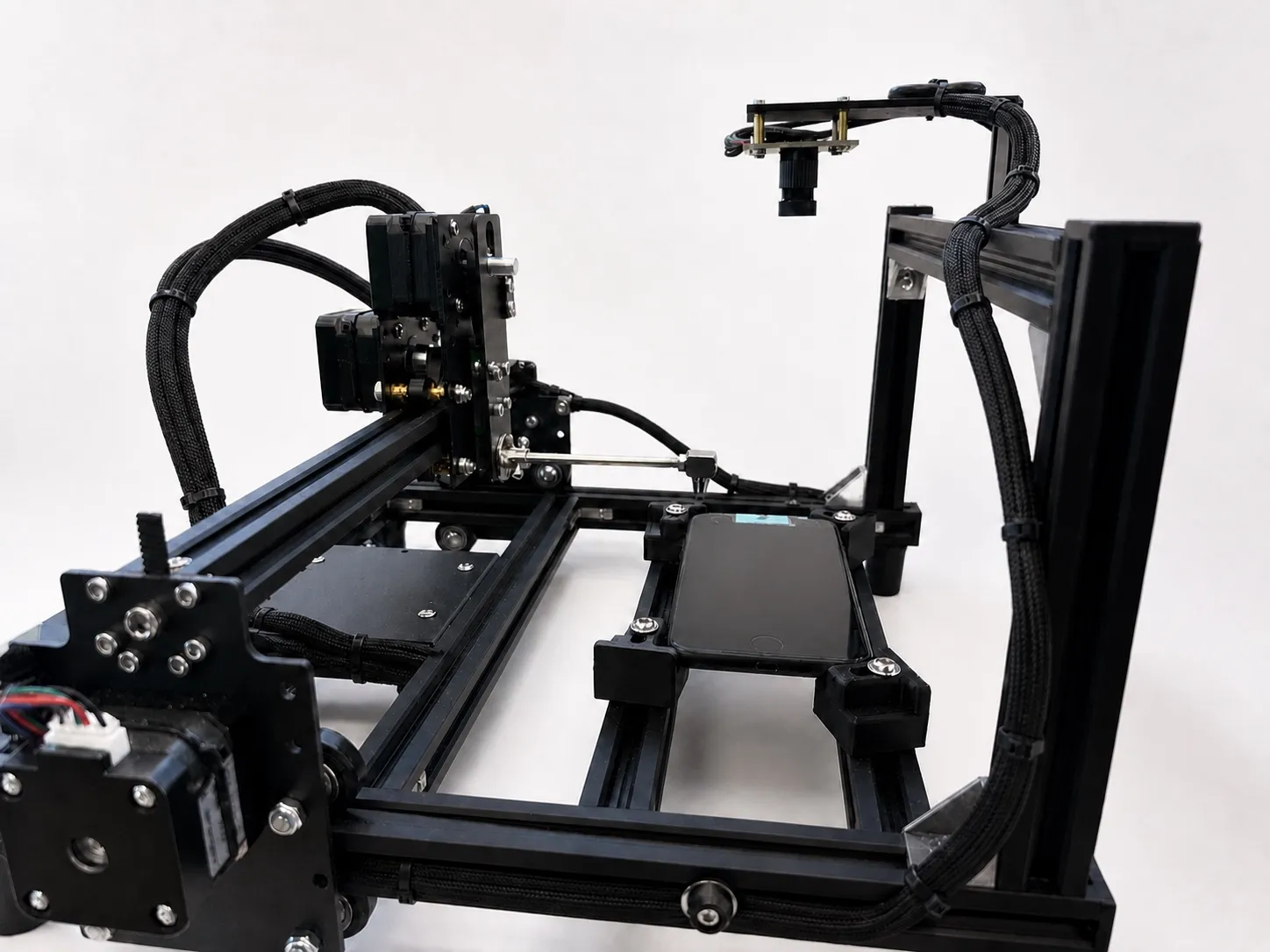 The phonebase robot cell: an XY gantry with an overhead camera over an unmodified retail iPhone